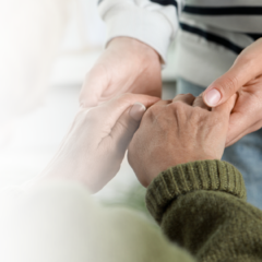 A caregiver holding the hands of a senior with dementia