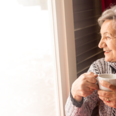 Senior woman enjoying a warm drink by a window during winter